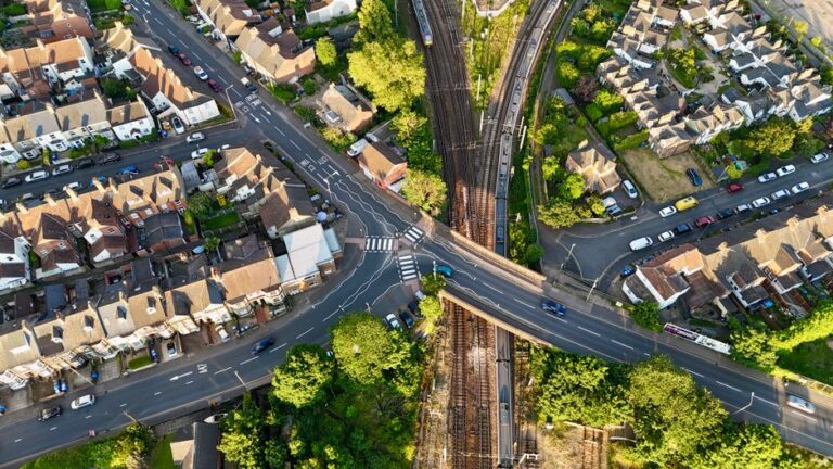 Aerial view of a residential intersection and railway in Norfolk, England, showcasing urban planning.