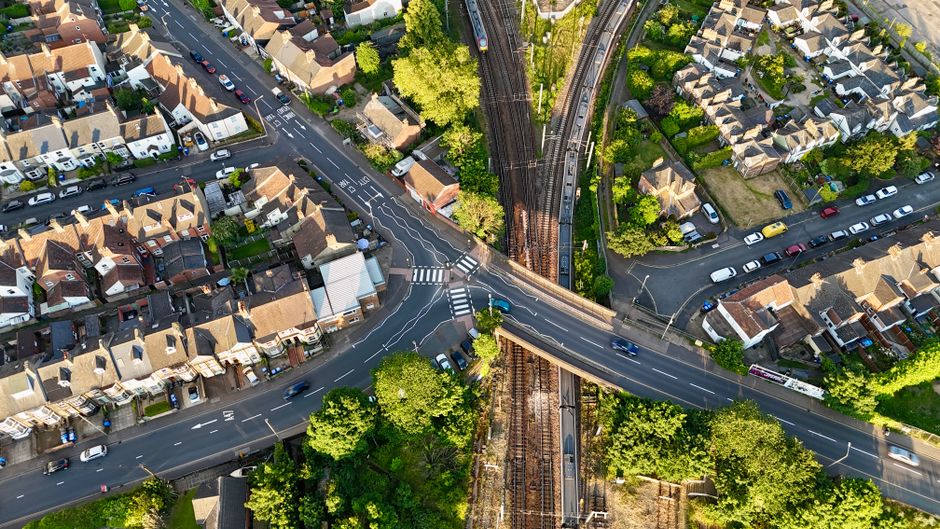 Aerial view of a residential intersection and railway in Norfolk, England, showcasing urban planning.